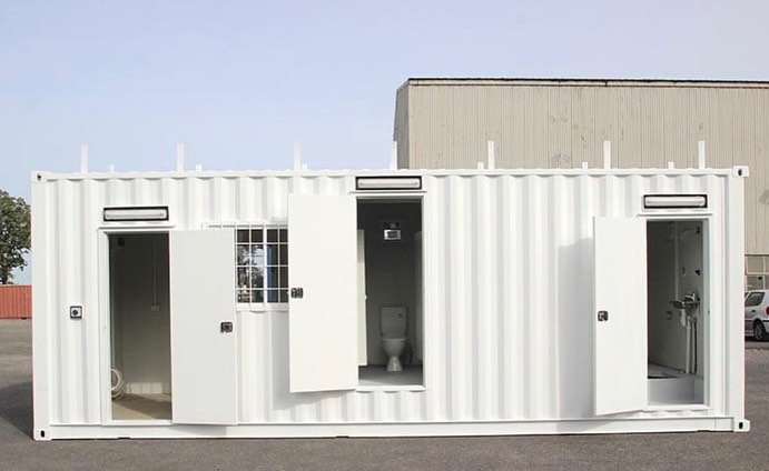 Portable white shipping container toilet and shower block for construction sites.