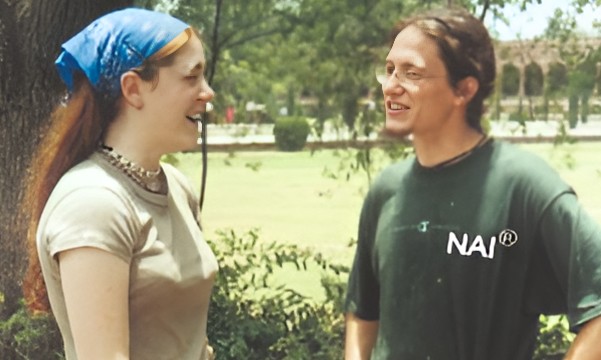 a man and woman standing in front of a tree