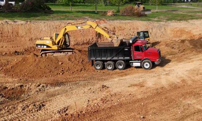 dump truck and excavator digging out a pond