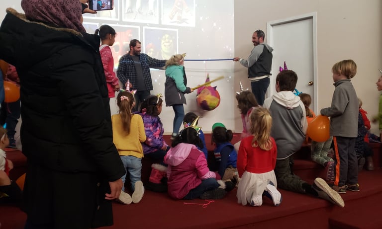 a group of children and adults celebrating birthday hitting a pinata