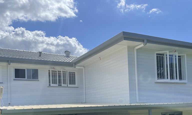 Completed exterior repaint in Zillmere showing bright white house finish under blue sky