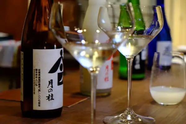 Japanese sake bottle with kanji label next to tasting glasses at Kyoto brewery