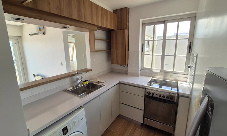 Remodelación de cocina en departamento con mesada blanca y muebles de madera