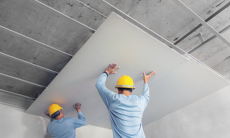 two men in hard hats and hard hats are working on a ceiling