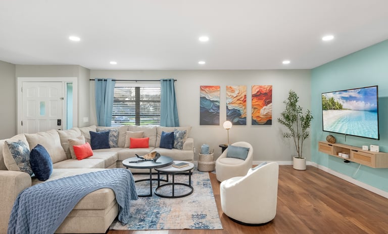 Modern living room featuring a beige sectional sofa, colorful wall art, and a wall-mounted TV.