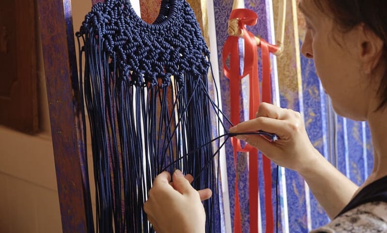 Las manos de una mujer tejiendo con destreza un intrincado tapiz de macramé