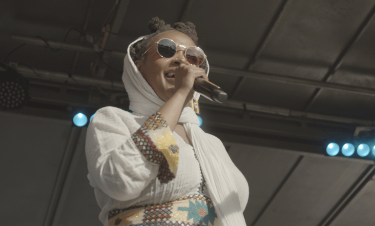 A person performing on a stage holding a microphone.