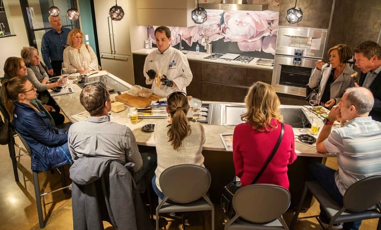 Chef Andrew giving a cooking demonstration in a luxury kitchen appliance showroom.