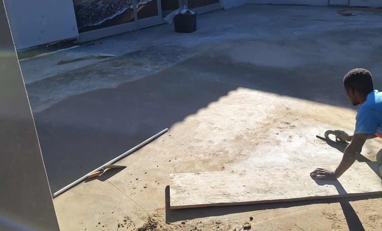 Worker applying slope screed to correct drainage on flat slab surface