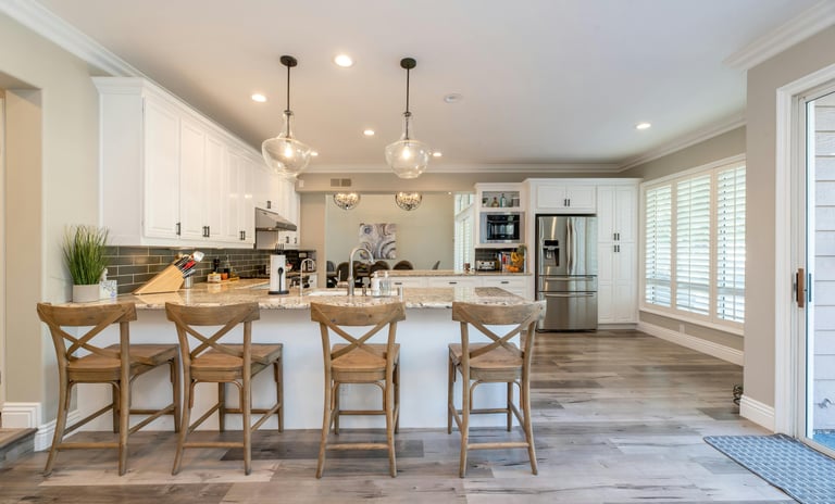 bright open kitchen and dining area with natural light, spotless counters, and welcoming table setti