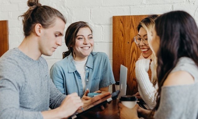 a group of people sitting at a table with a tablet