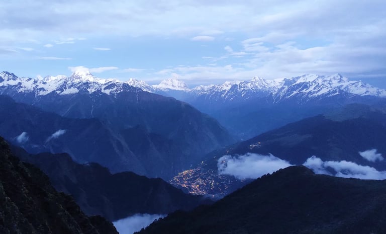 Snow-capped mountains and valleys under an evening sky