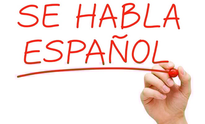 a hand writing spanish words on a white board