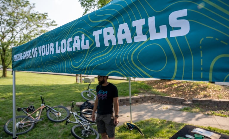 Someone standing under the COMOTA tent with bikes laying on the ground