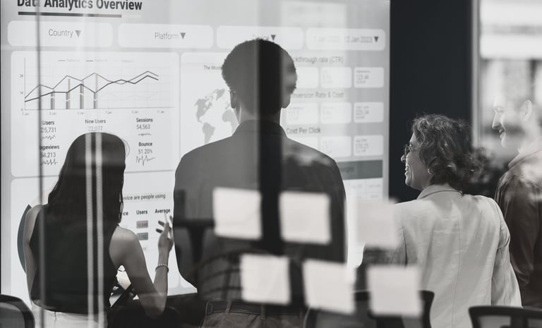a group of people standing in front of a white board looking at slide titled Data Analytics Overview