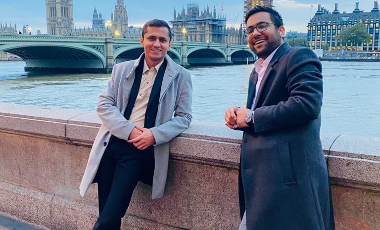 two men standing next to each other on a bridge