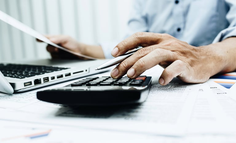 Plumber typing on calculator while working on JobberBooks bookkeeping.