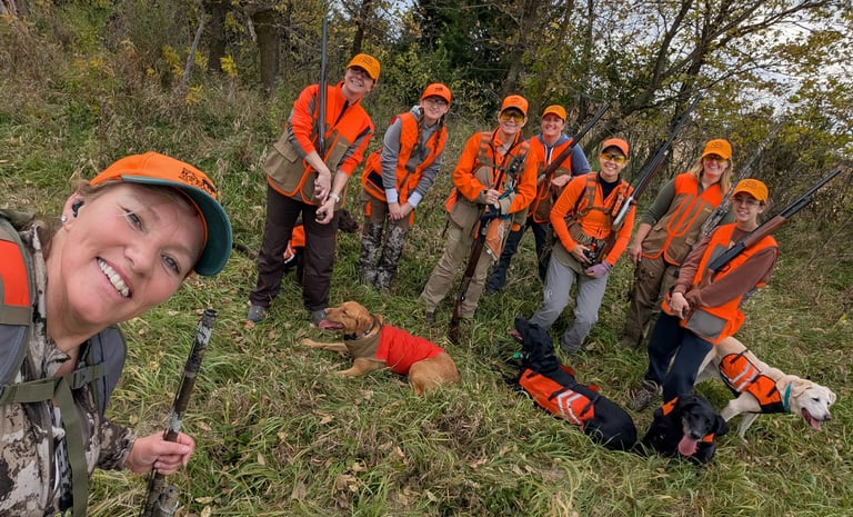Group of women posing with dogs after a pheasant hunt.