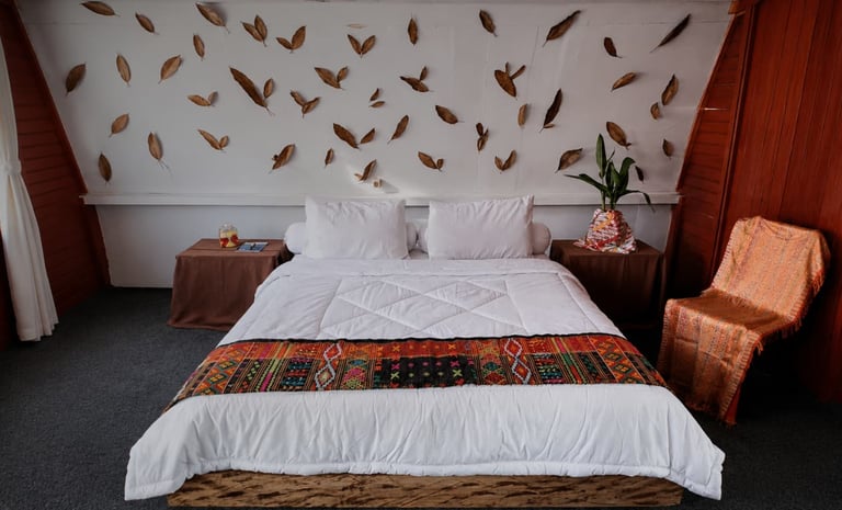 Cozy rustic bedroom with a white duvet, traditional patterned runner, and autumn leaf wall decor.