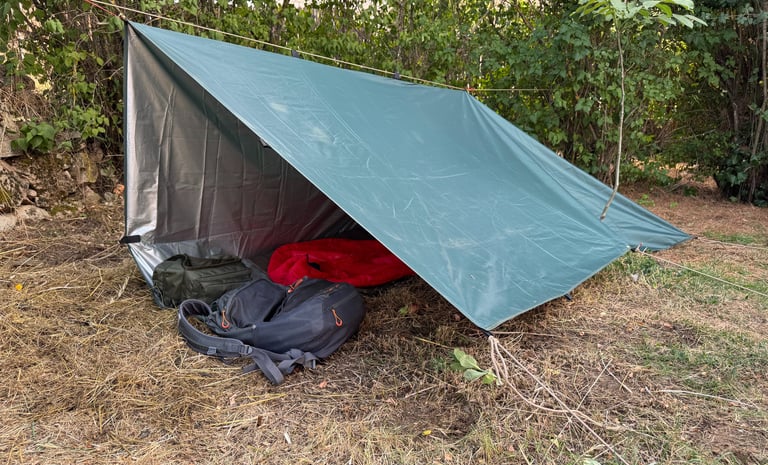 vista exterior de un refugio de fortuna construido con un tarp y línea de cordino