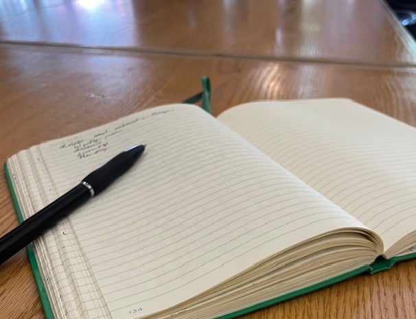 Image of open lined journal with pen on wooden table 