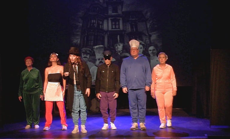 Actors in colorful costumes a musical number in front of a haunted house backdrop.