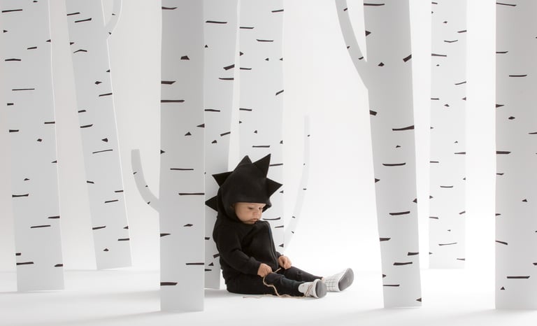 Fashion photography - a baby in a dinosaur outfit with trees