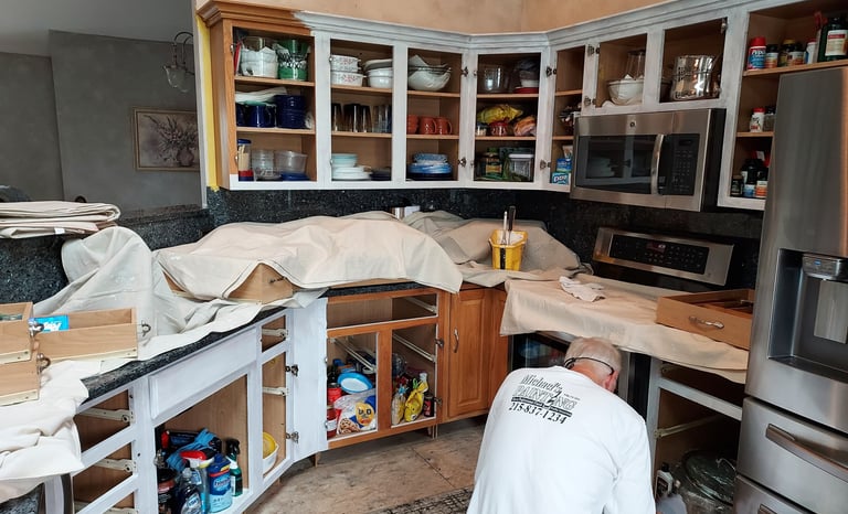 a man in white painting kitchen cabinets