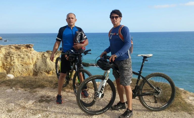 two men standing next to each other on a cliff
