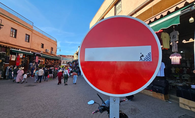 Détournement de panneaux de signalisation représentant un homme détruisant un mur sur sens interdit 