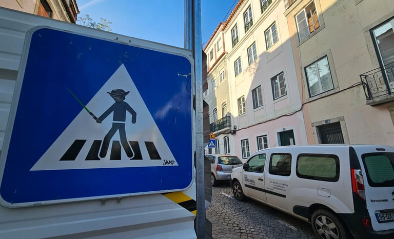 Street art sur panneau de signalisation représentant Yoda sur un panneau piéton à Lisbonne.