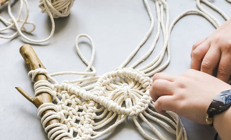 Manos creando un tapiz de macramé DIY usando cuerda de algodón blanca