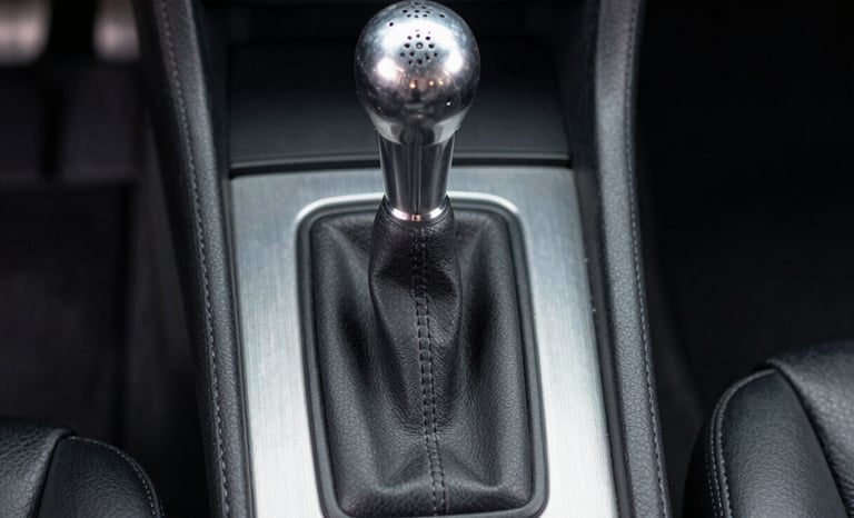 Close-up technical shot of a gated manual shifter in a classic sports car, brushed aluminum console, clean leather boot, straight-on eye-level framing.