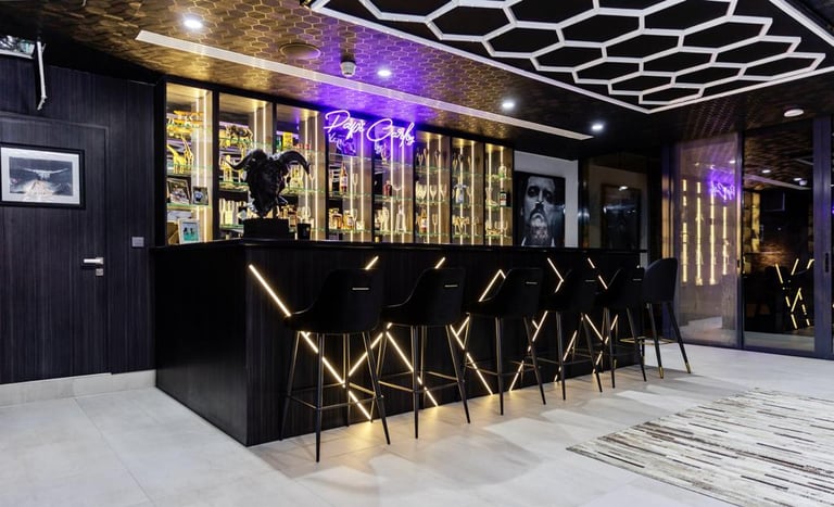 Chic indoor bar with black and gold accents and neon lighting.