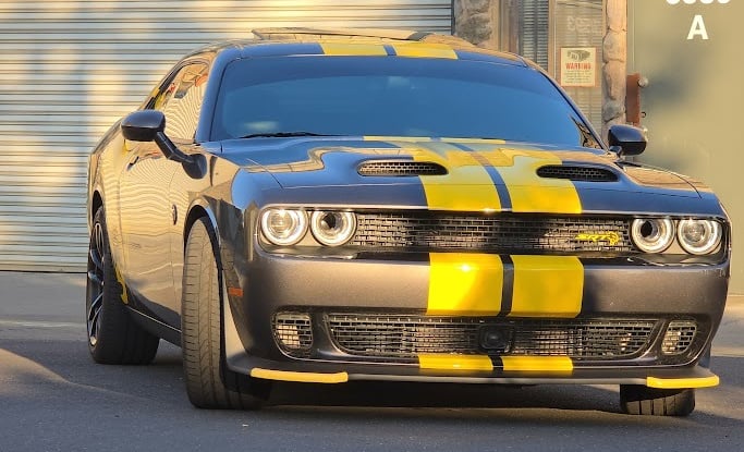 Custom automotive vinyl job: Yellow racing stripes applied from front to back on a black Dodge Chall
