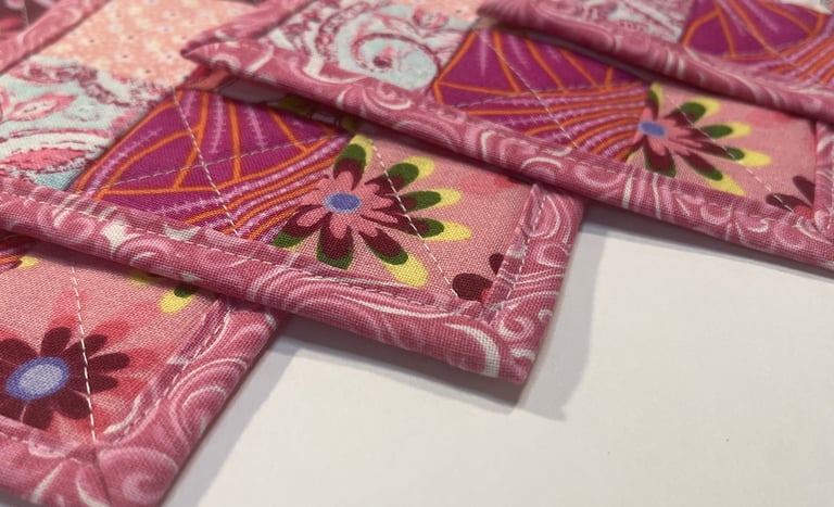 a bunch of small quilted coasters with pink flowers