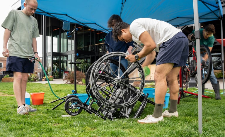 Person washing a wheelchair wheel with a sponge and suds