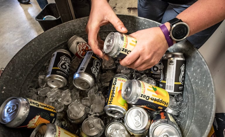 Hands grabbing a beer from a bucket of beers on ice
