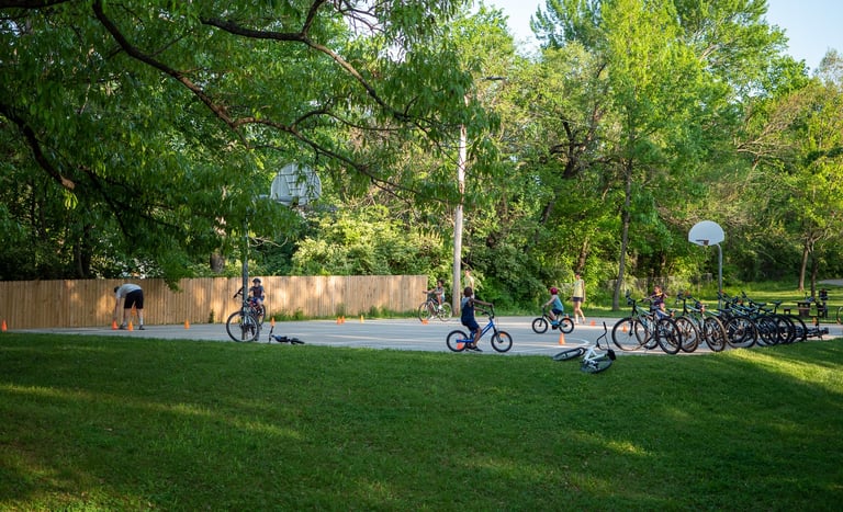 Kids completing a biking course around cones in a park