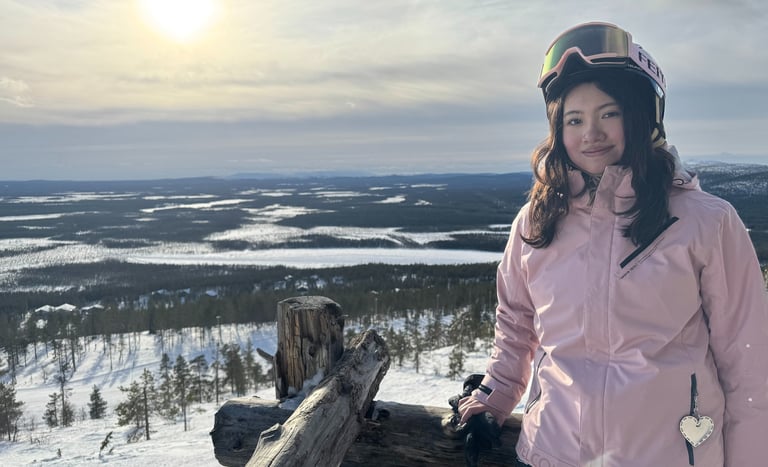 a woman in a pink jacket and helmet on a snowy day on top of a hill
