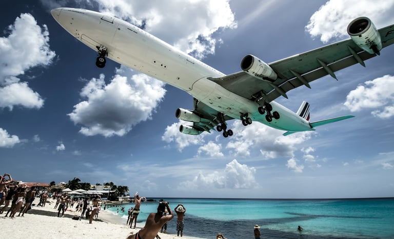 An airplane descending to land over a sandy beach