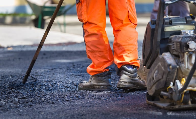 Asphalt contractor leveling and compacting new pavement on commercial parking lot in San Antonio