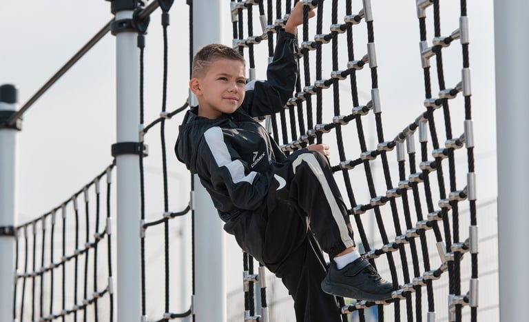 Garçon grimpant sur une structure Kenguru Pro Kids Active Play en extérieur.