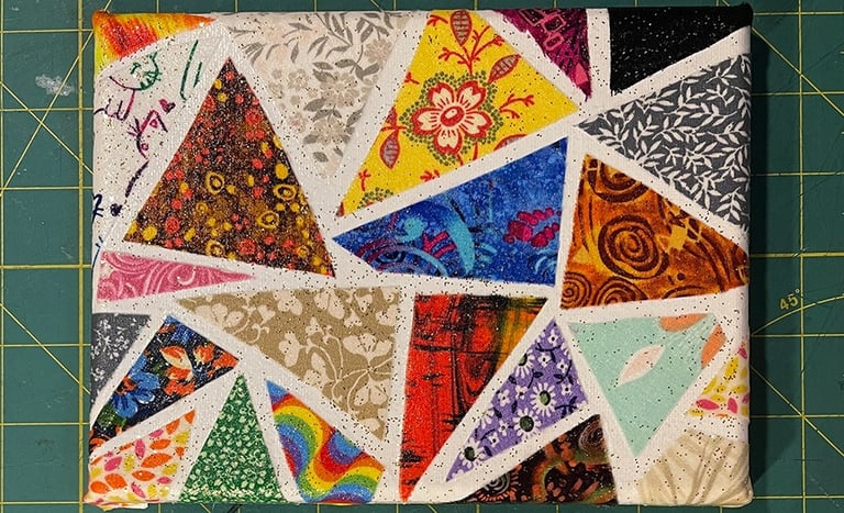 a piece of art work made with colorful triangle fabric scraps