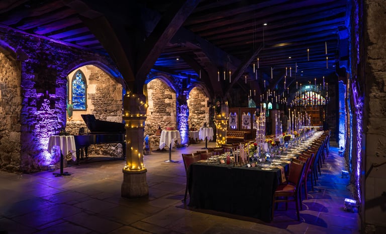 Indoor event setup with elegant lighting and long dining tables, themed Harry Potter
