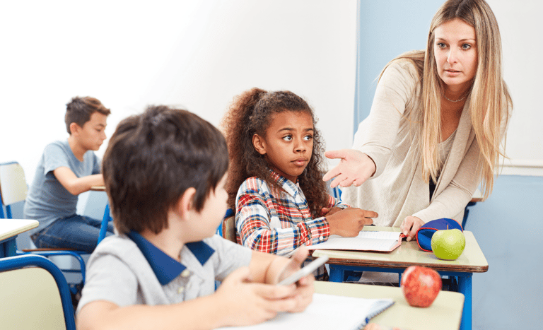 Teacher asking boy for his cell phone in the classroom.