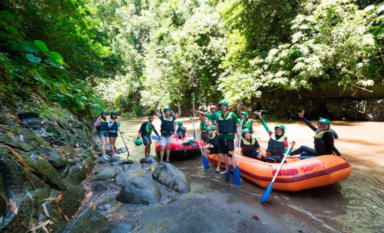 Group of tourists in life jackets and helmets enjoying white water rafting on a tropical river.