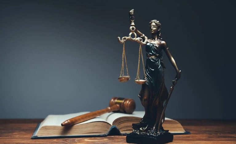 Foto de uma estátua da deusa themis ao lado de um martelo de juiz