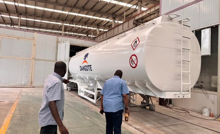 Two men inspecting a white Dangote fuel tanker trailer inside our industrial warehouse facility.