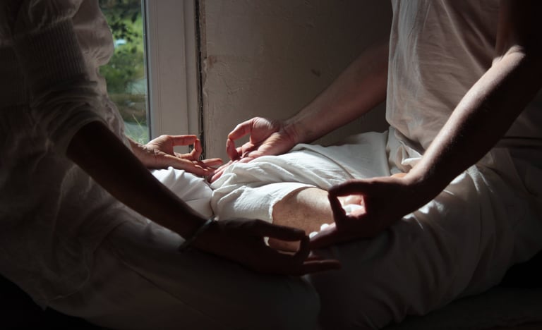 Deux personnes font un mudra de yoga, face à face.